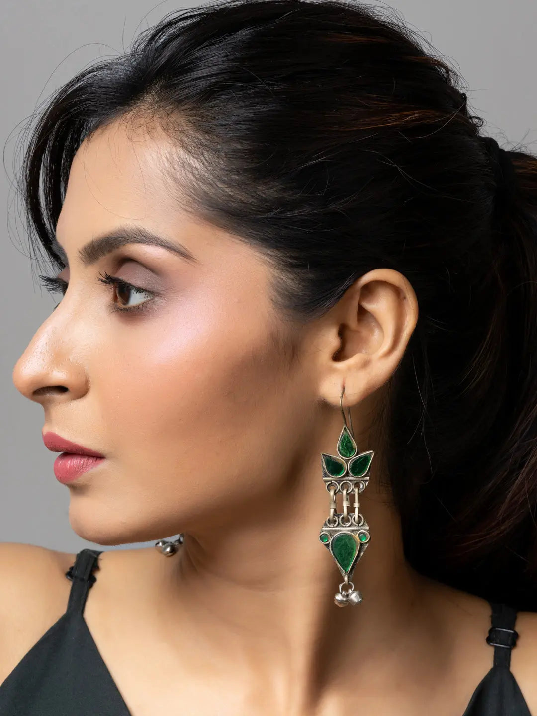 Woman wearing green gemstone afghani earrings with intricate silver detailing from LOOK AND ADORN