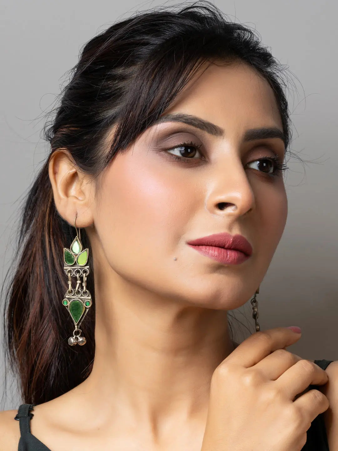 Woman wearing ornate afghani earrings with green stones and silver detailing
