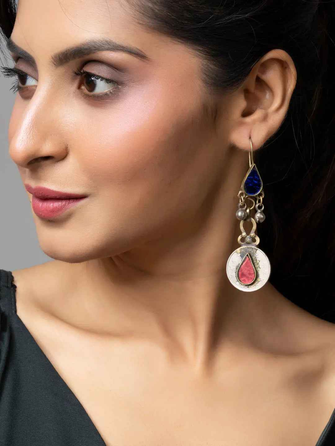 Close-up of a woman wearing detailed afghani earrings with blue and red accents from LOOK AND ADORN