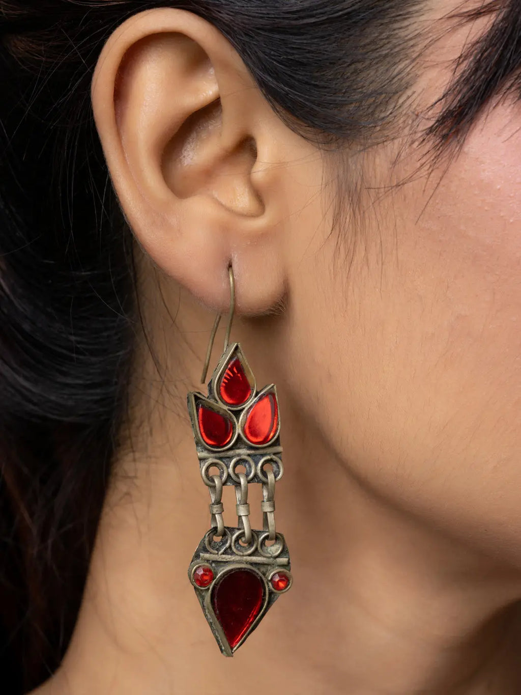 Close-up of a woman wearing traditional red and silver afghani earrings from LOOK AND ADORN collection