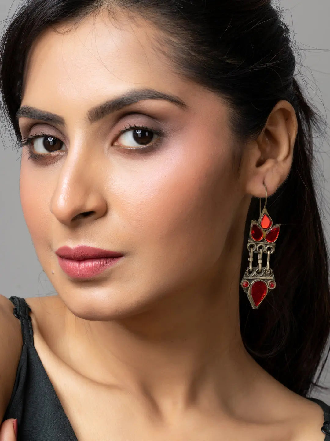 Close-up of a woman wearing red and silver decorative afghani earrings from LOOK AND ADORN
