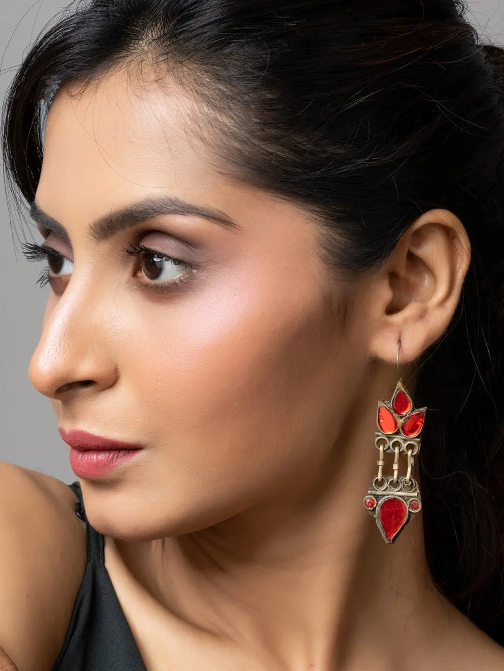 Woman wearing traditional Afghani earrings with red stones and intricate metalwork from LOOK AND ADORN