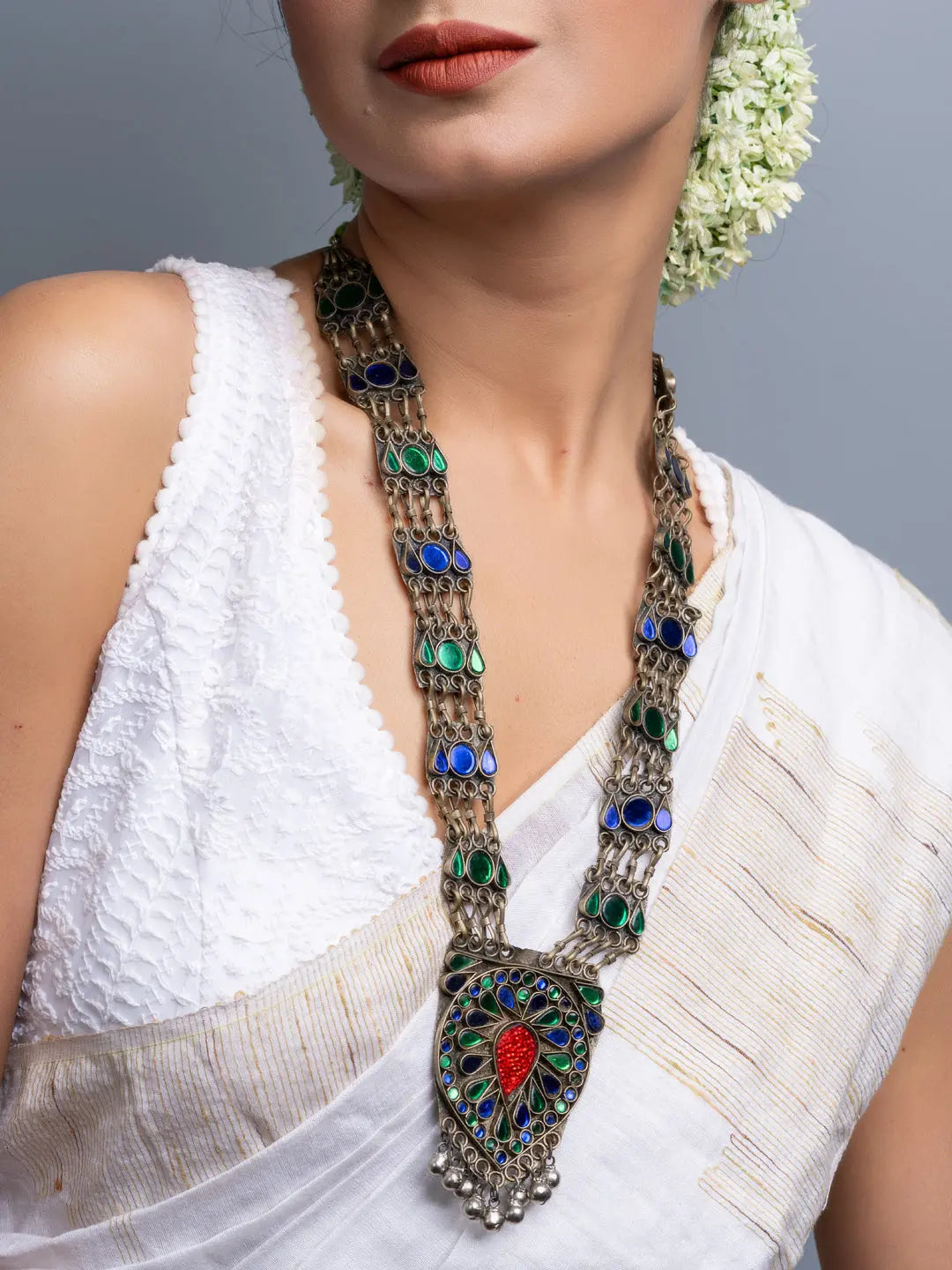 Elegant Afghani necklace with intricate blue and green stones and traditional design worn with white attire