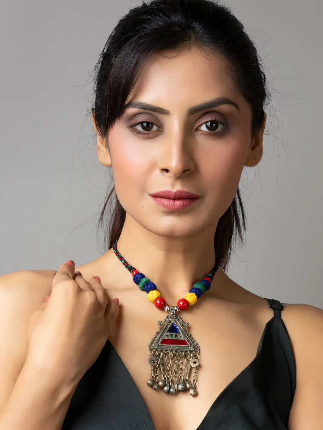 Woman wearing colorful afghani necklace with triangular pendant and dangling charms from LOOK AND ADORN