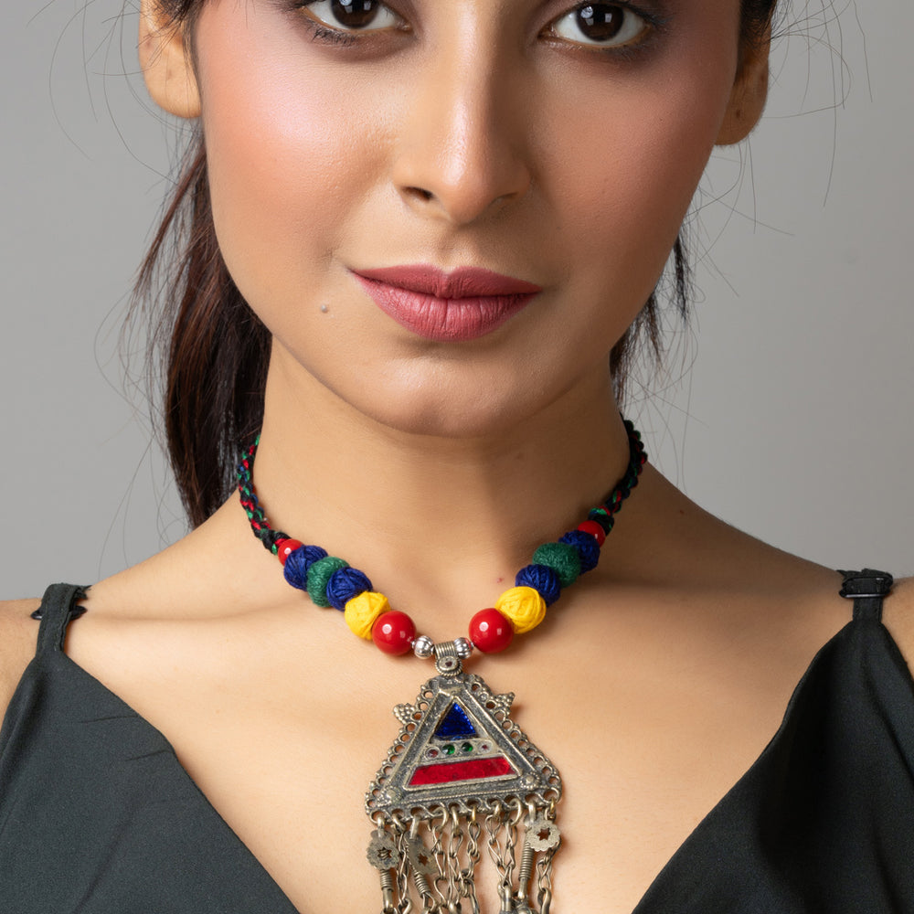 Woman wearing colorful Afghani necklace with triangular pendant and dangling silver beads
