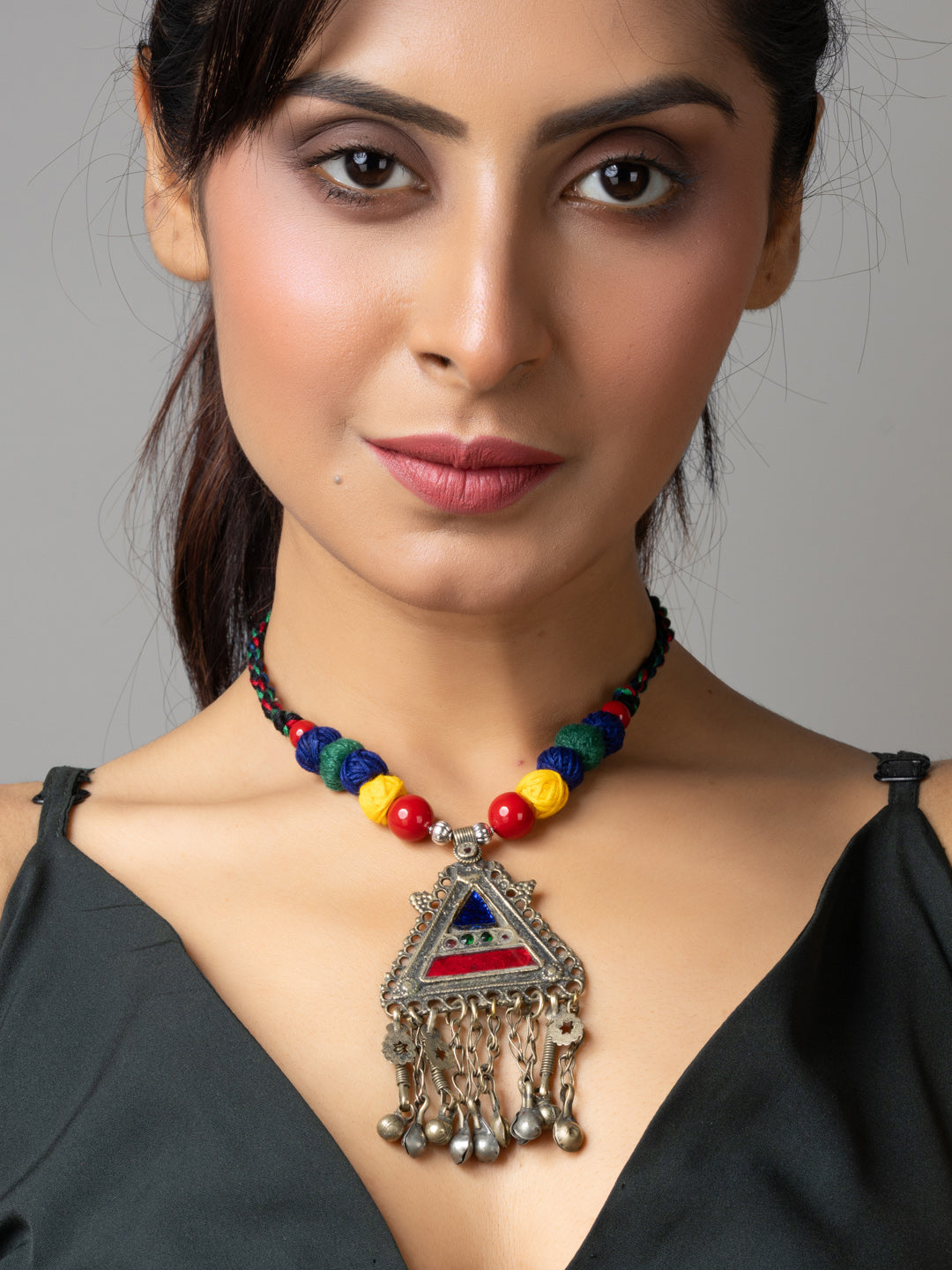 Woman wearing colorful Afghani necklace with triangular pendant and dangling silver beads