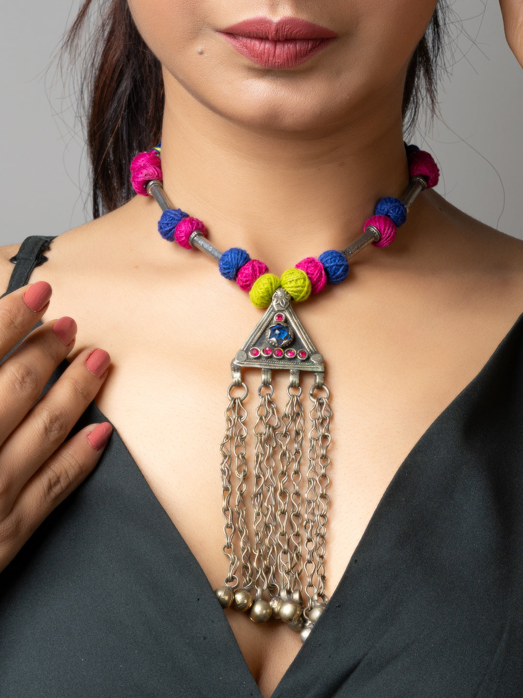 Colorful Afghani necklace with triangle pendant and hanging silver chains worn on woman in black dress