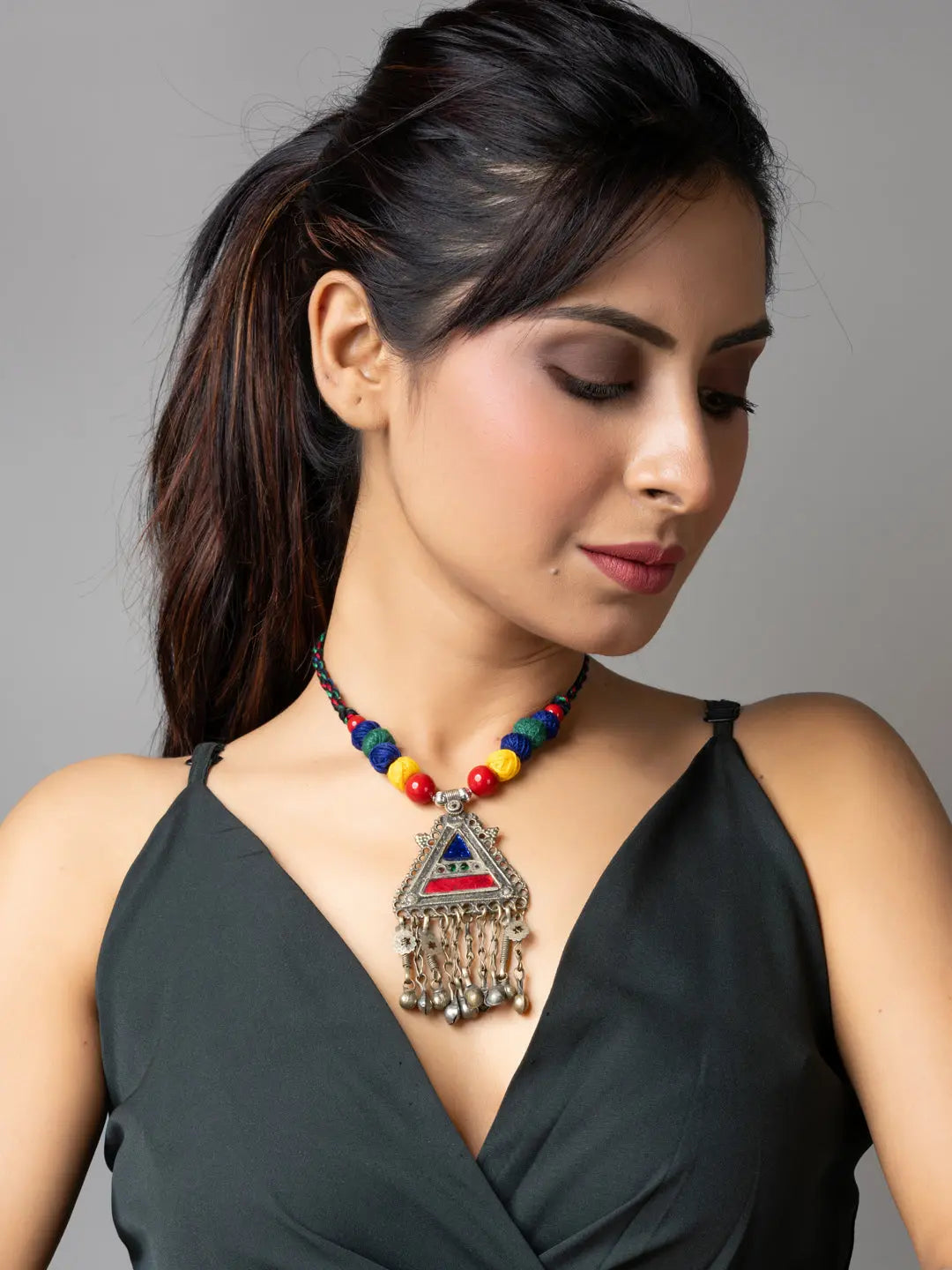 Woman wearing a colorful afghani necklace with a triangular pendant and bead details