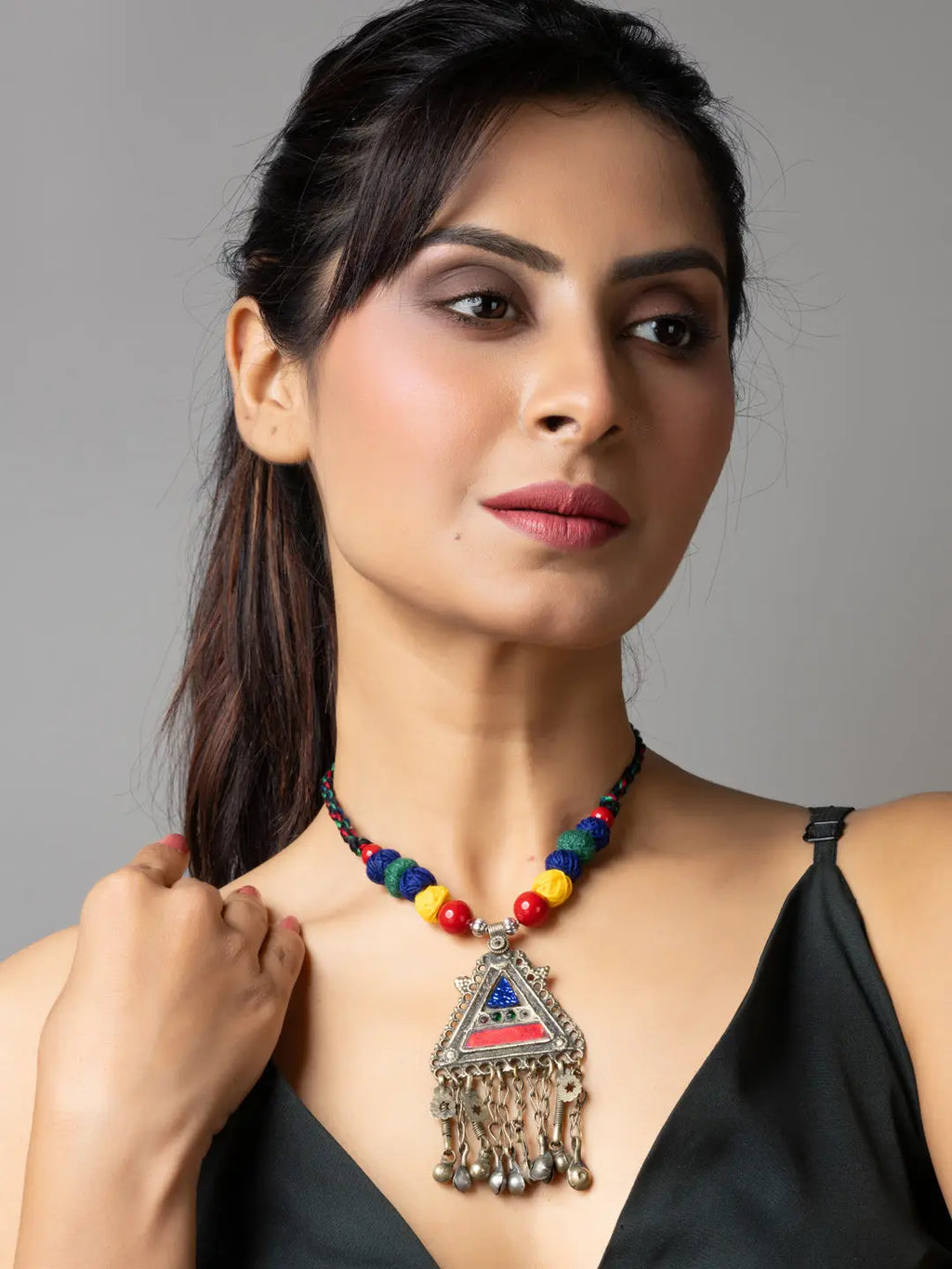 Woman wearing a colorful beaded afghani necklace with a silver triangular pendant and dangling charms