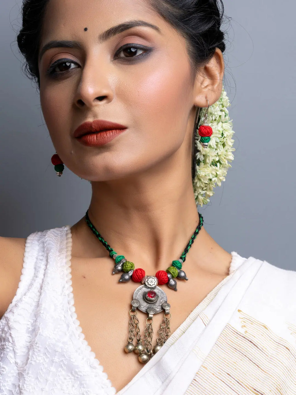 Elegant afghani necklace set with silver pendant and colorful beads worn by woman in white outfit