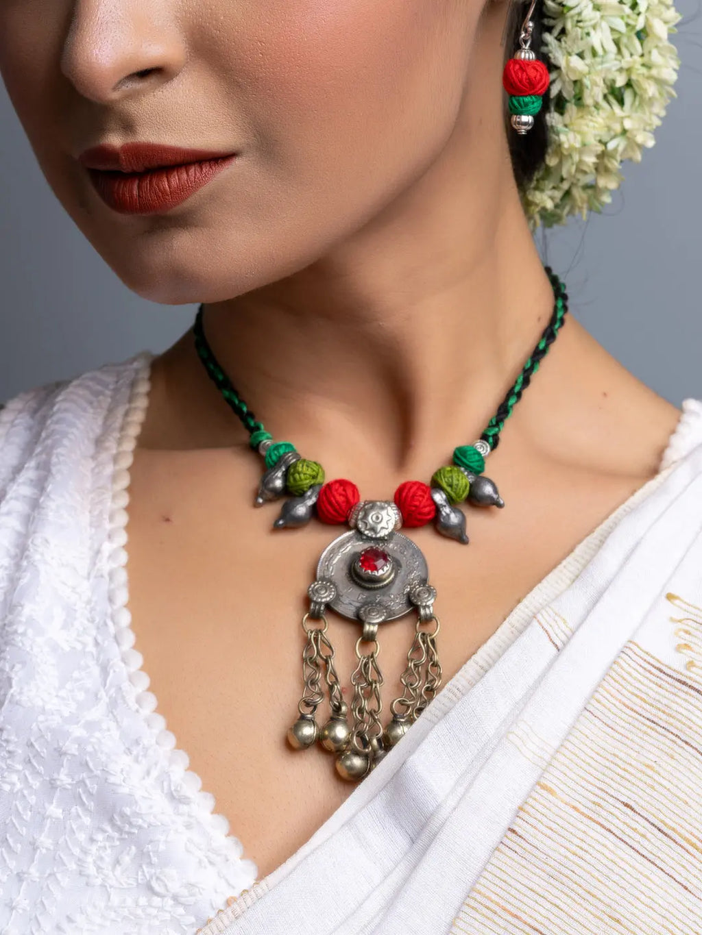 Afghani necklace set featuring colorful beads and antique silver pendant with dangling chains worn by woman