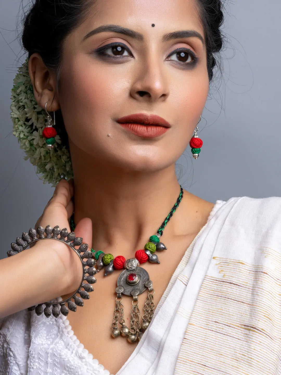 Afghani necklace set with red and green beads and intricate metal pendant worn by woman