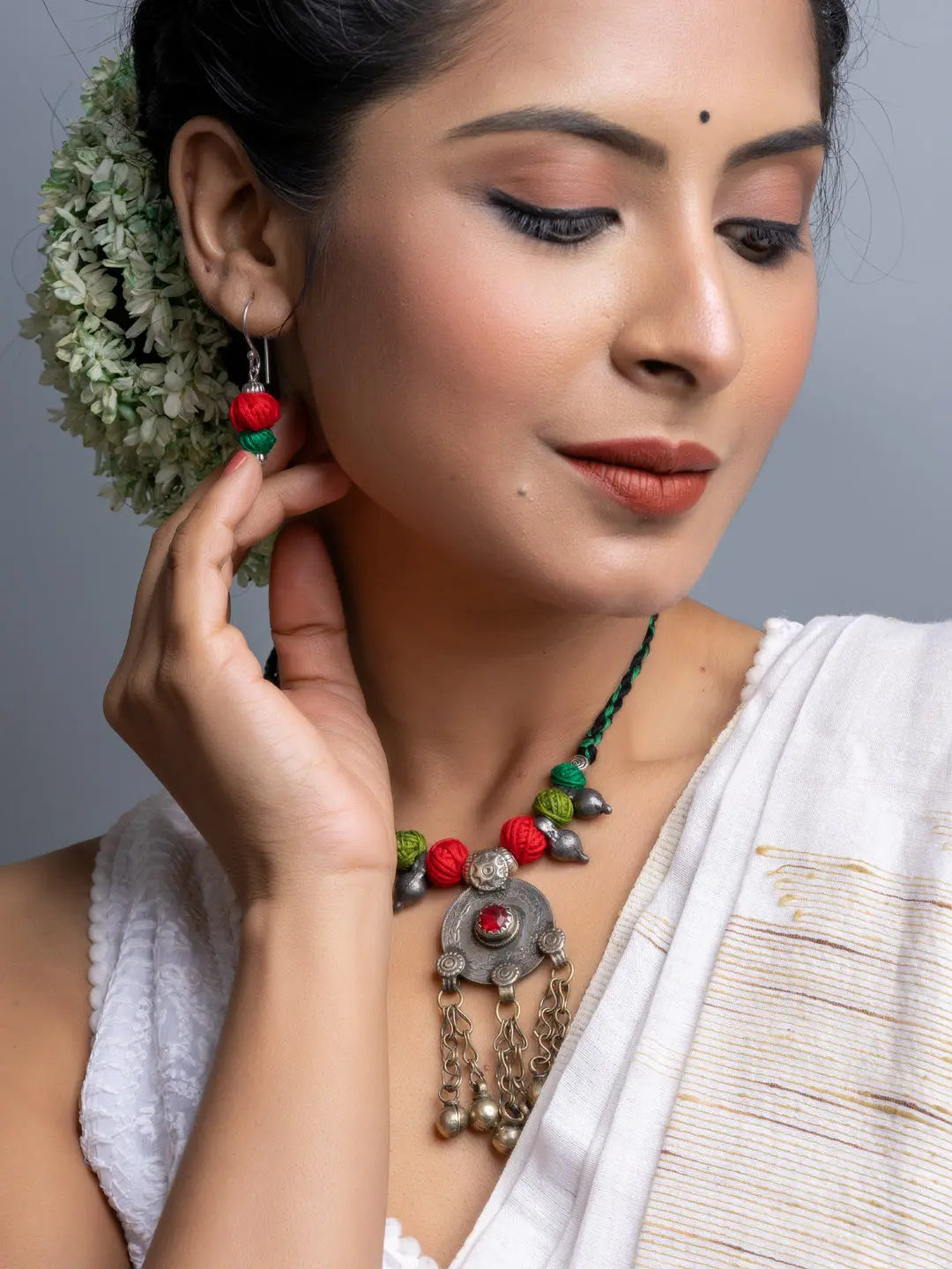 Woman wearing a colorful afghani necklace set with traditional silver pendant and matching earrings
