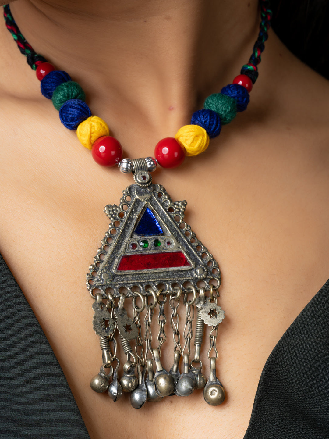 Colorful afghani necklace with a triangular pendant featuring red and blue stones and dangling silver charms