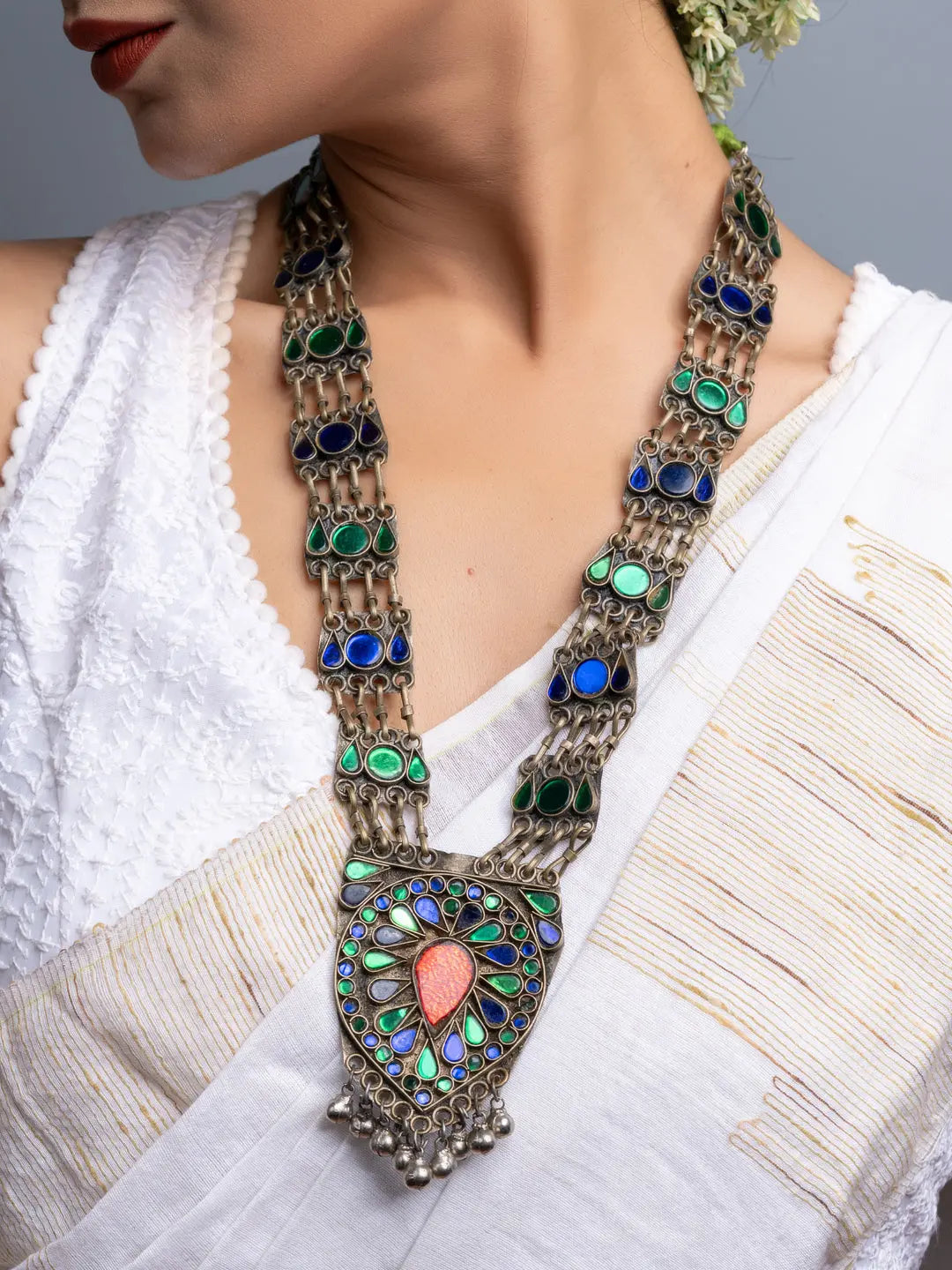 Afghani necklace with intricate blue and green stones worn with traditional white attire