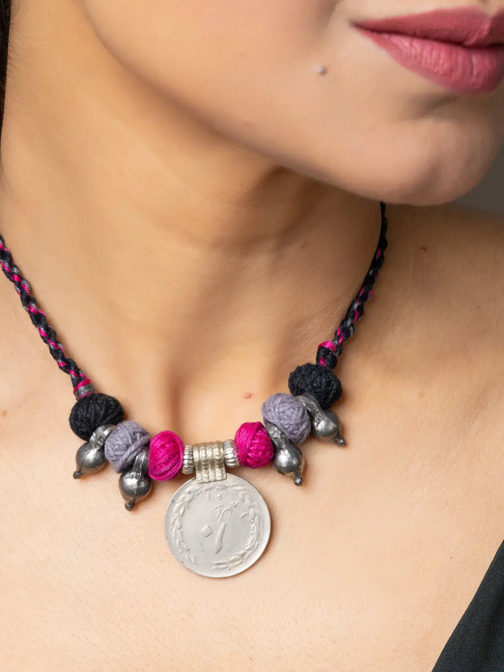 Close-up of a woman's neck wearing a LOOK AND ADORN afghani pendant with colorful beads and silver coin detail