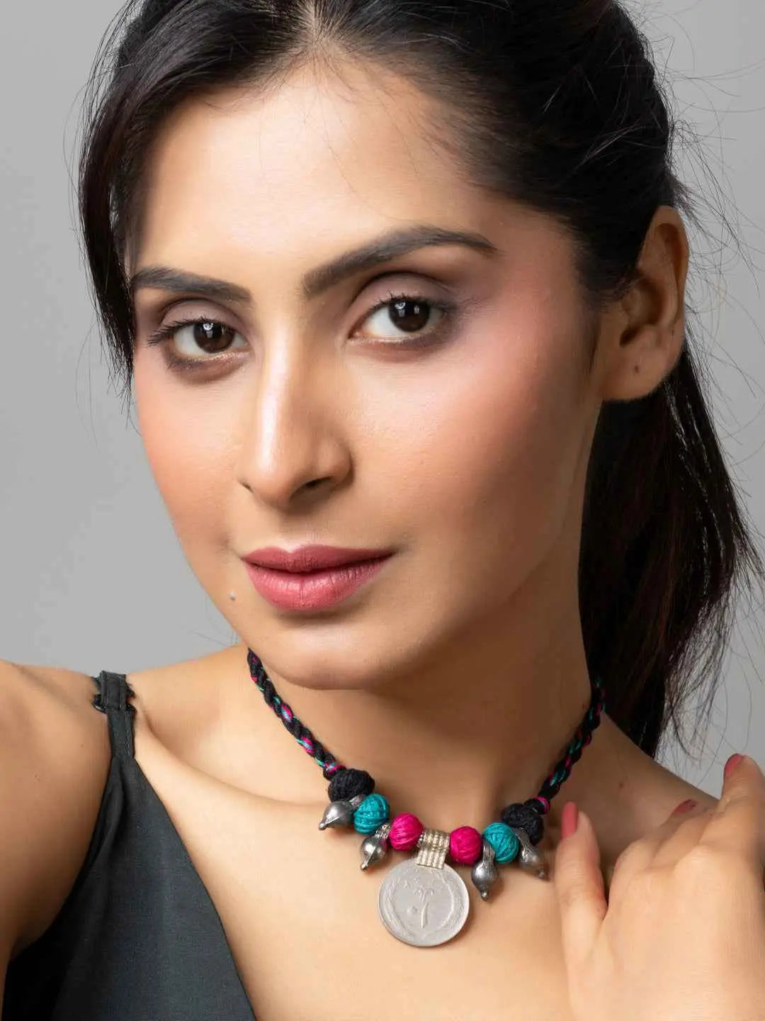 Woman wearing colorful afghani pendant necklace with beads and braided black cord