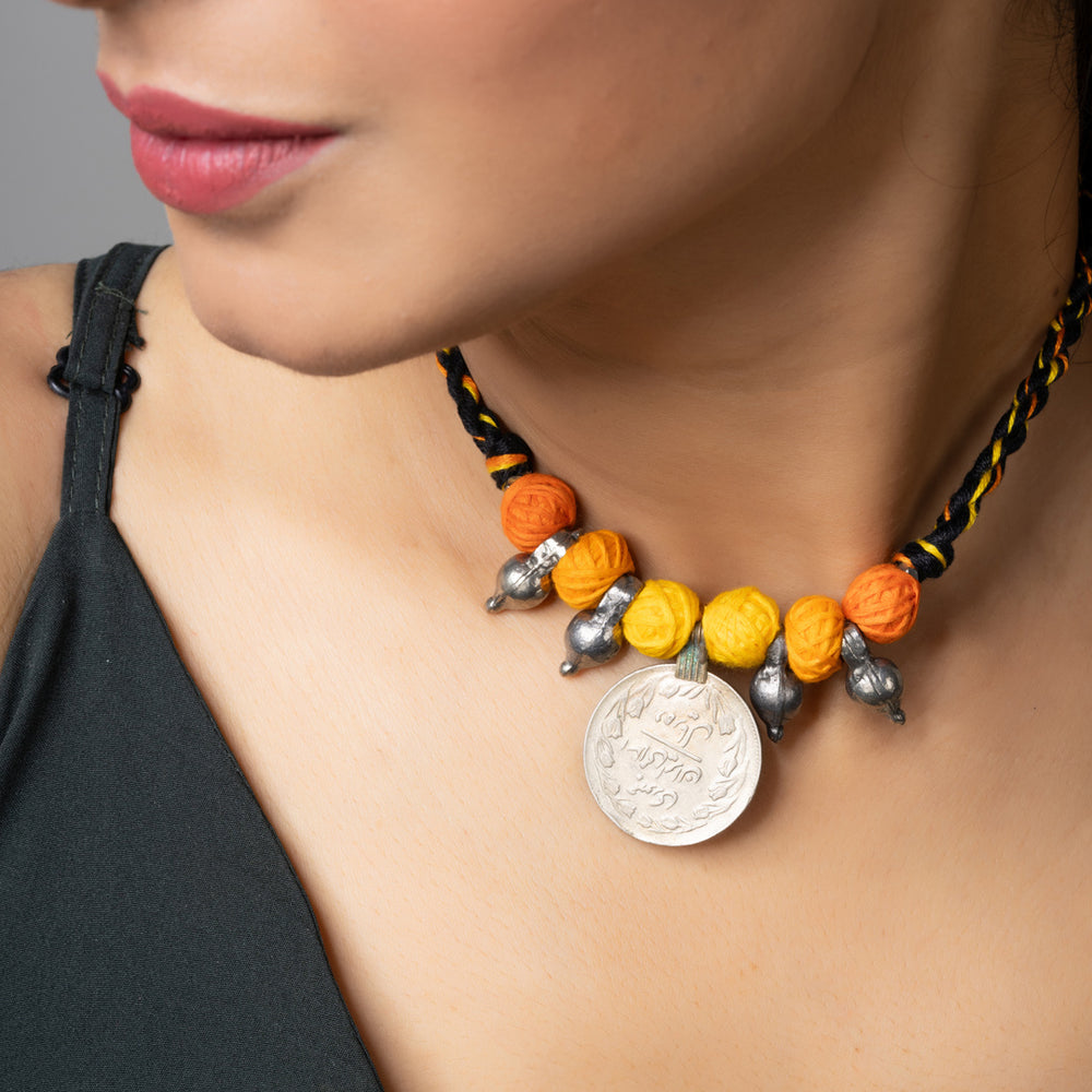 Close-up of a woman wearing a colorful handmade afghani pendant necklace with orange and yellow beads
