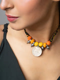 Close-up of a woman wearing a colorful handmade afghani pendant necklace with orange and yellow beads