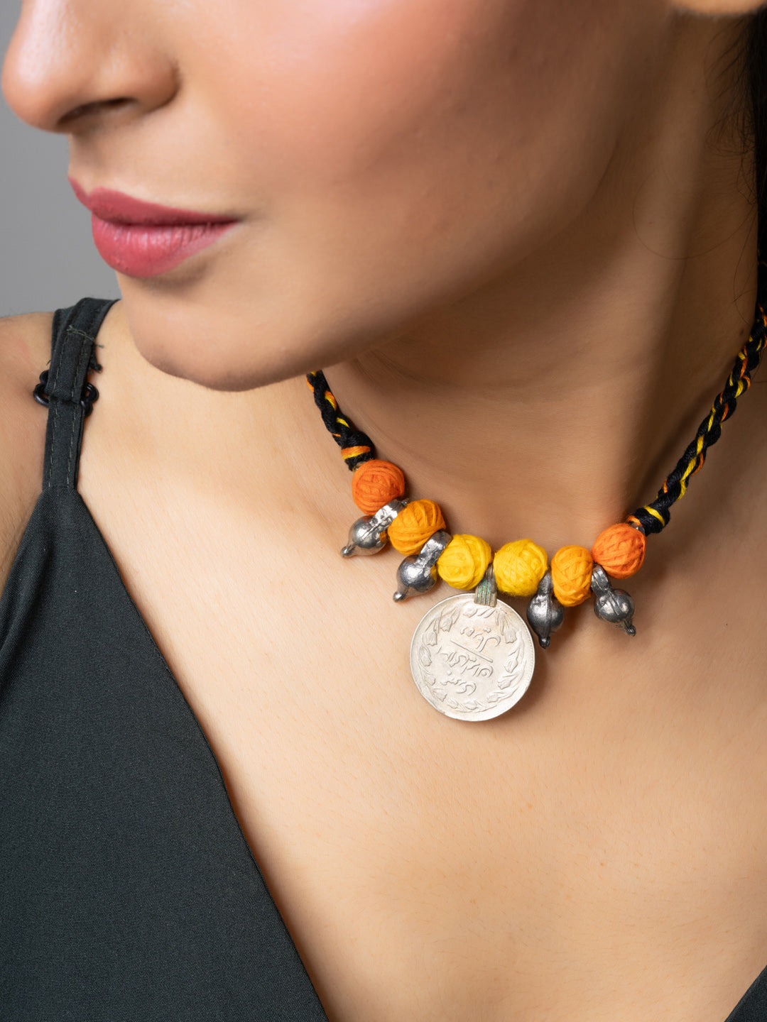 Close-up of a woman wearing a colorful handmade afghani pendant necklace with orange and yellow beads
