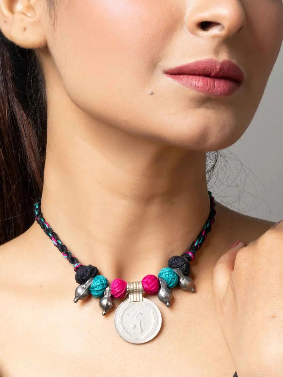 Close-up of a woman wearing a colorful afghani pendant necklace with turquoise and pink beads