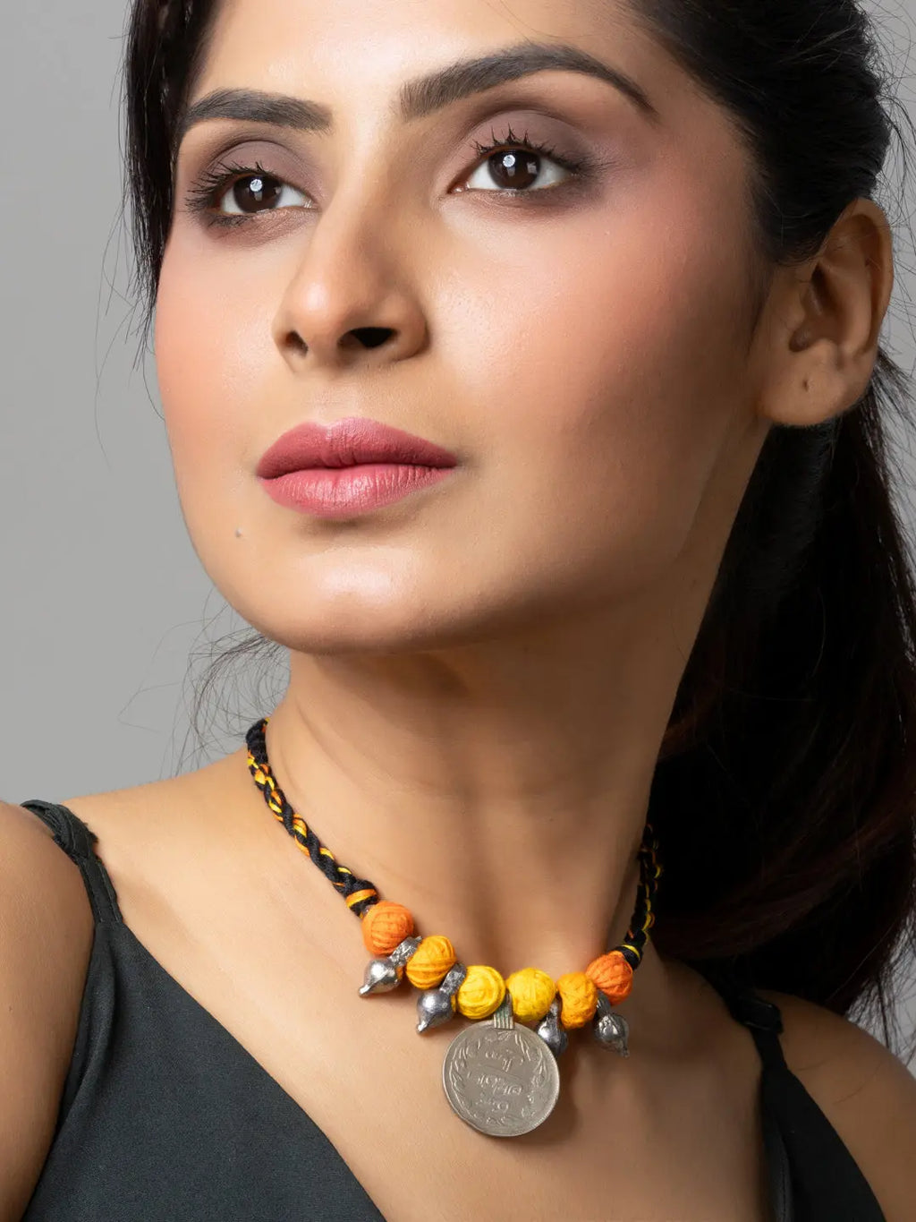 Woman wearing an afghani pendant necklace with yellow and orange beads on a black cord