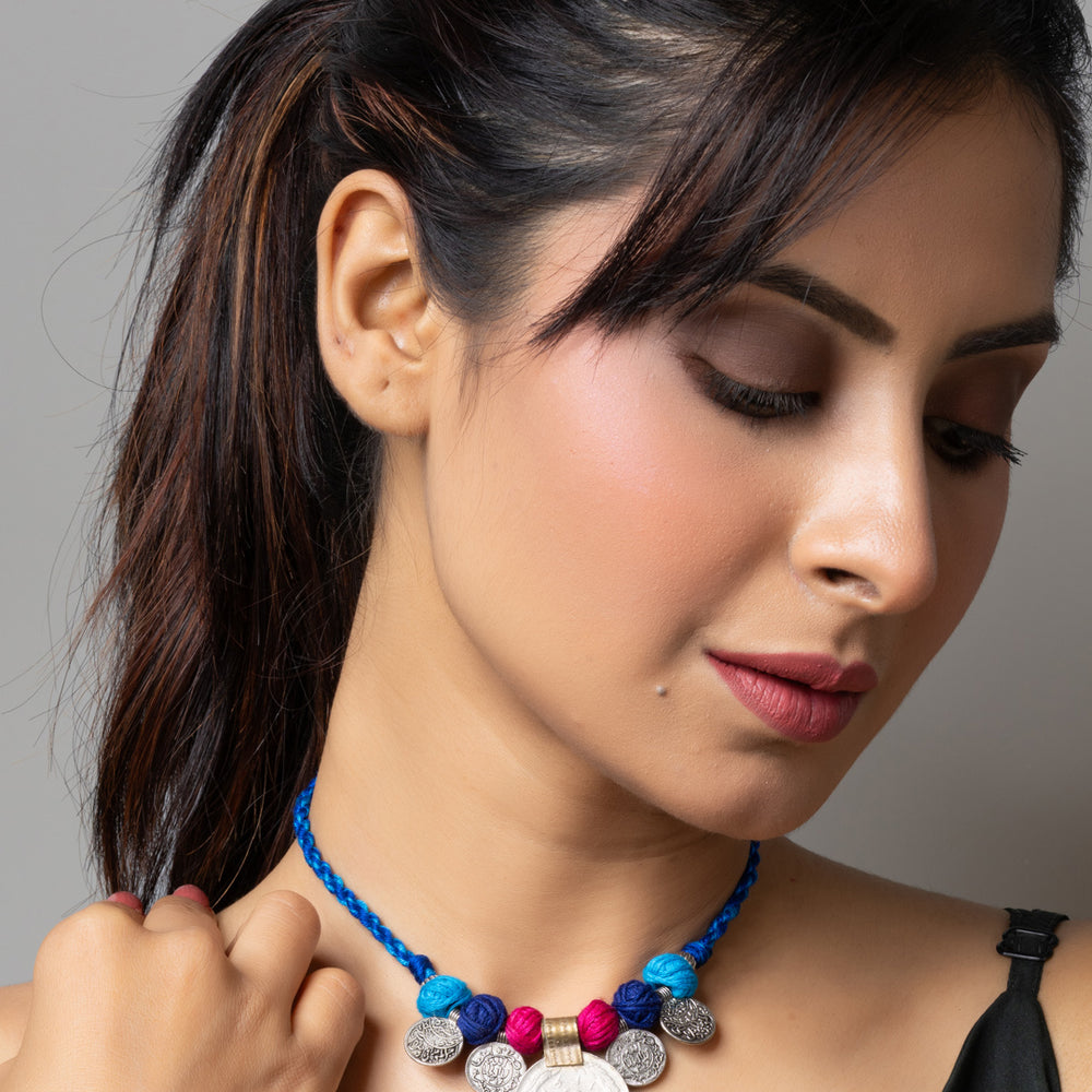 Woman wearing a colorful afghani pendant necklace with blue braided cord and intricate metal details