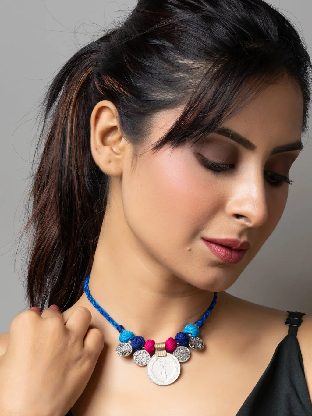 Woman wearing a colorful afghani pendant necklace with blue braided cord and intricate metal details
