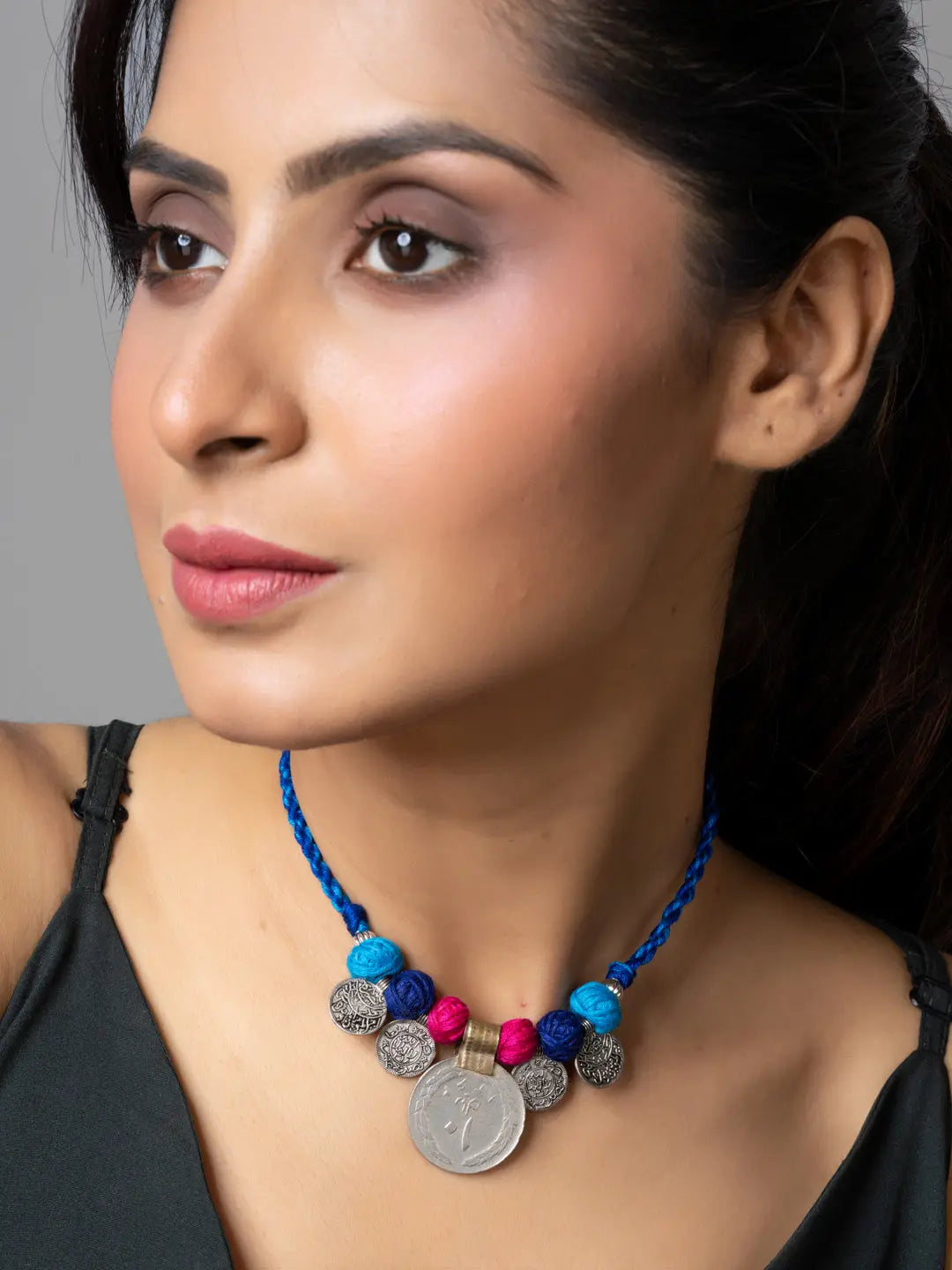 Afghani pendant necklace with blue and pink beads worn by woman in black top