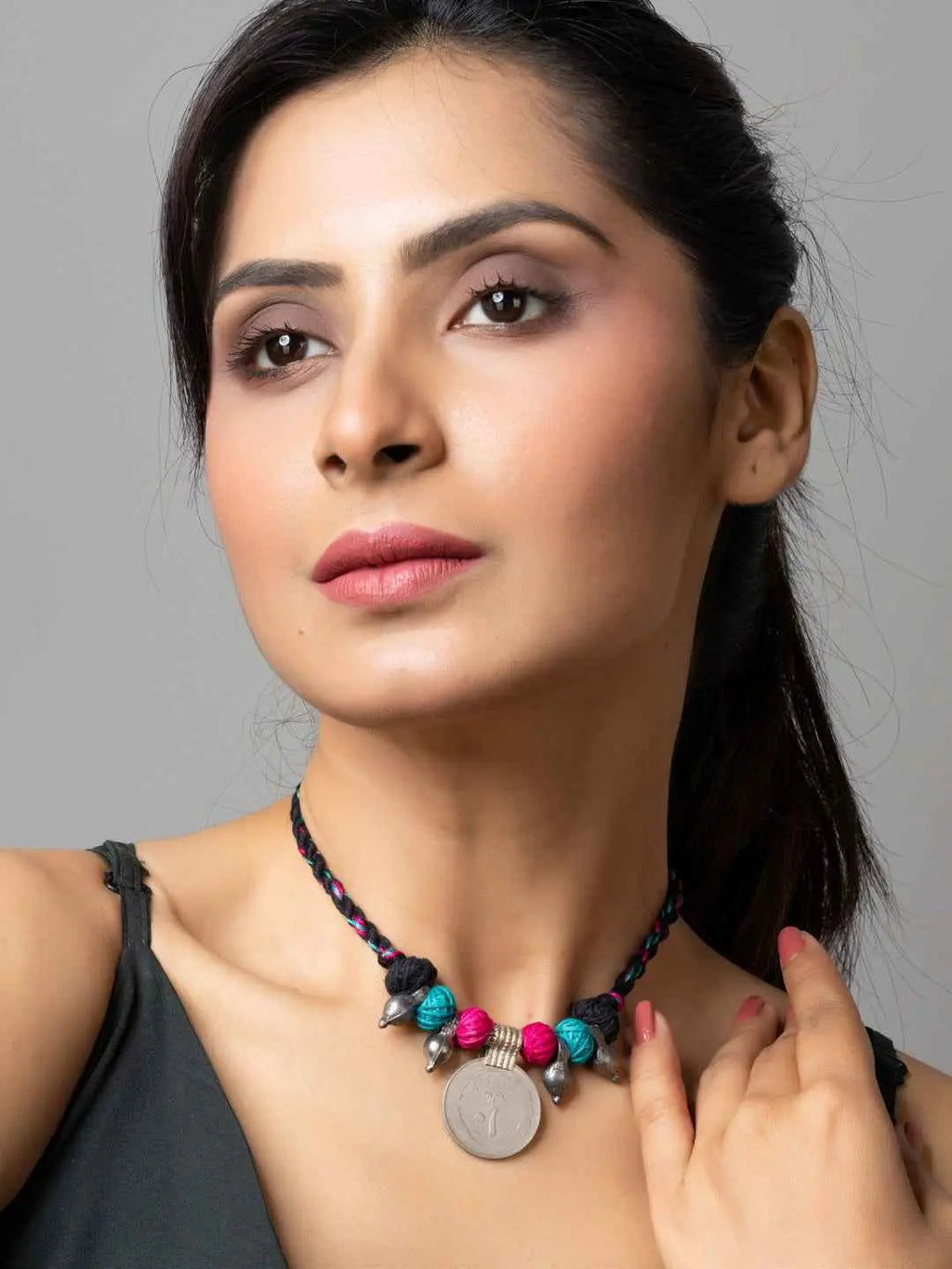 Woman wearing a colorful beaded afghani pendant necklace with blue and pink beads