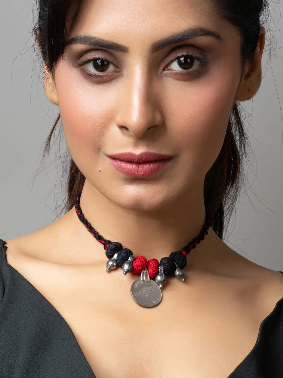 Woman wearing a handcrafted afghani pendant necklace with black and red beads and silver accents