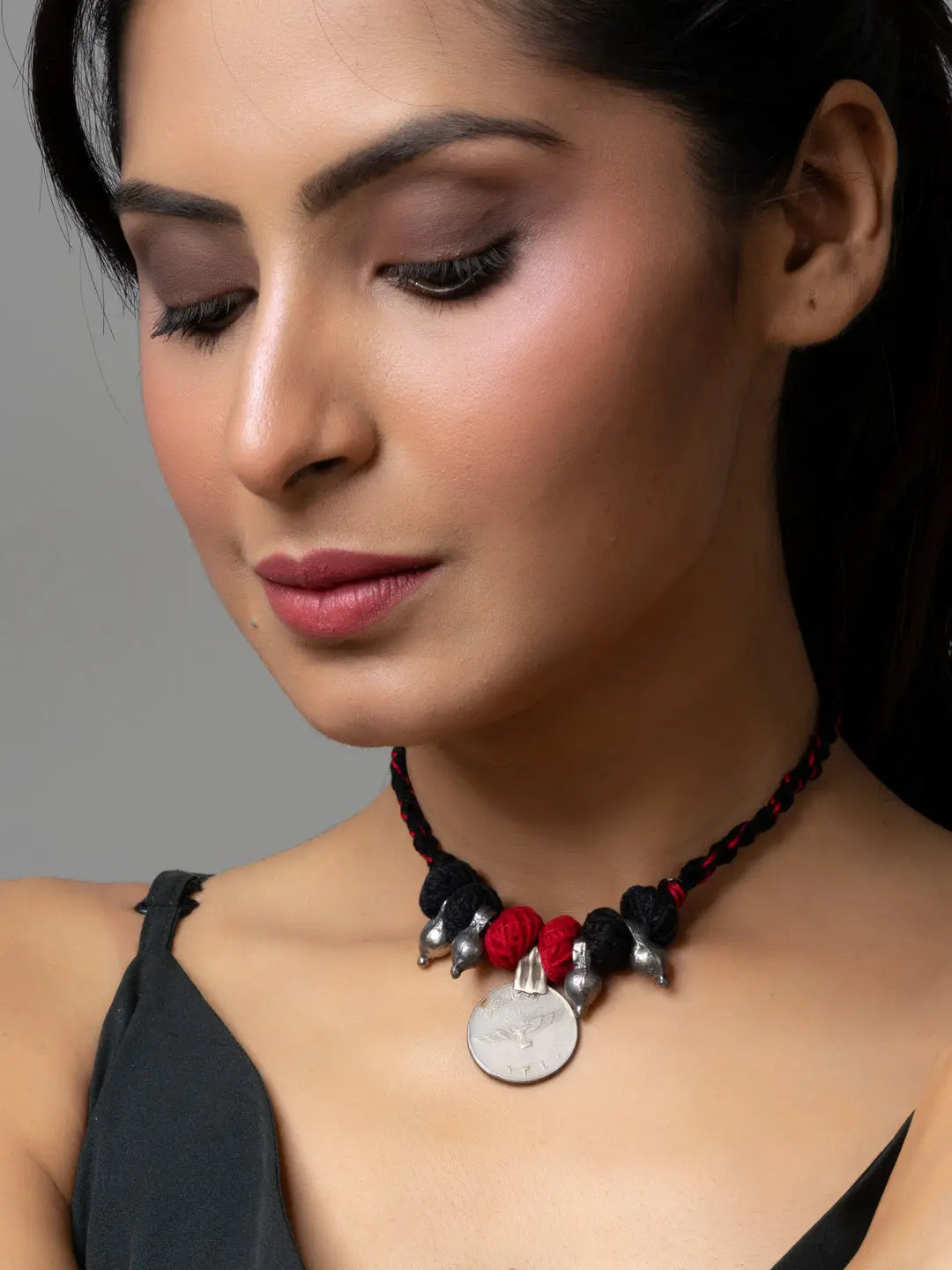 Woman wearing handcrafted afghani pendant necklace with red and black beads and silver accents