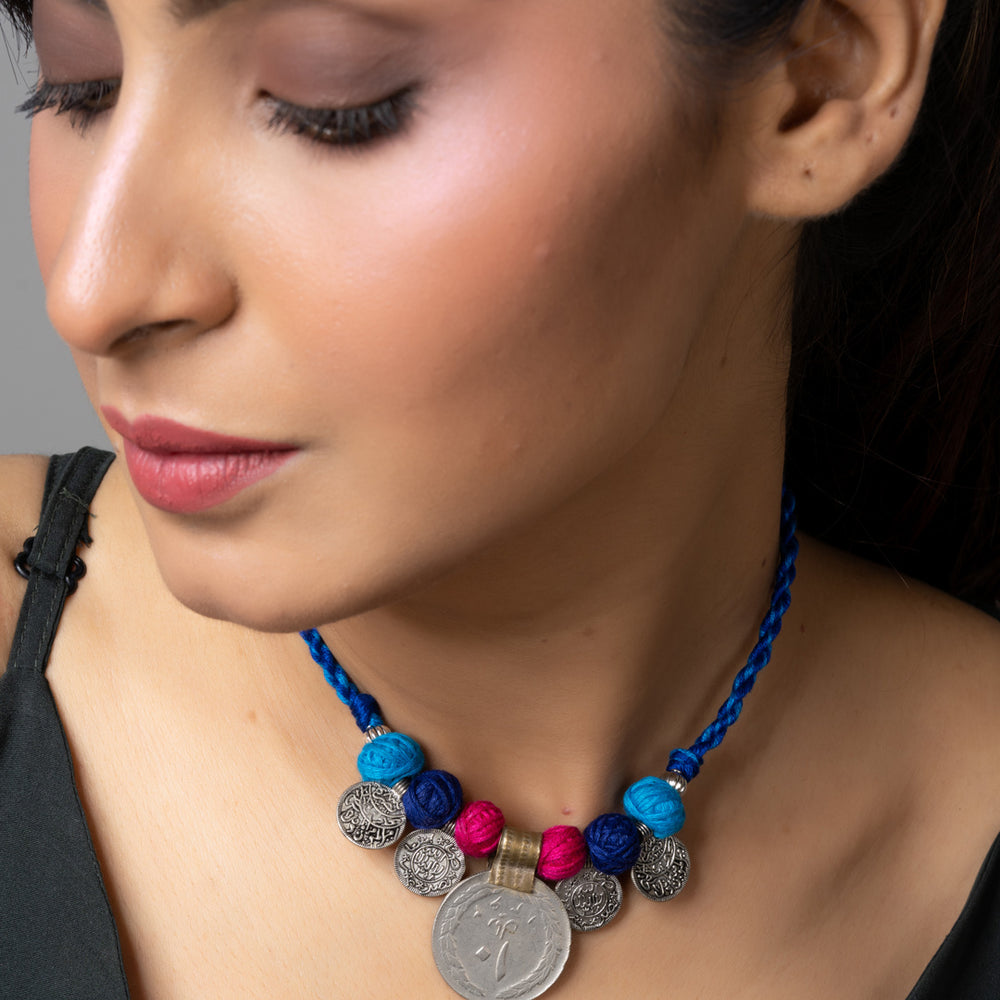 Woman wearing a colorful Afghani pendant necklace with blue, pink, and silver beads