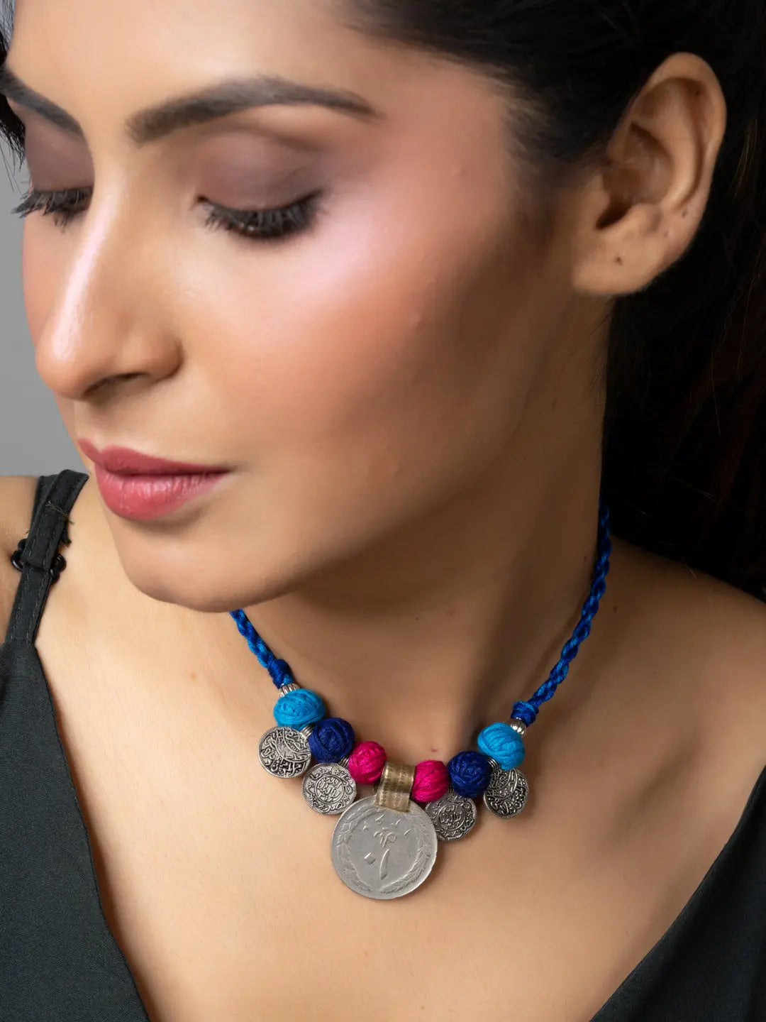 Woman wearing a colorful Afghani pendant necklace with blue, pink, and silver beads