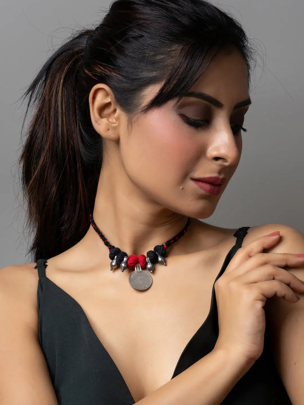 Woman wearing a black dress and stylish afghani pendant necklace with silver charm and red beads