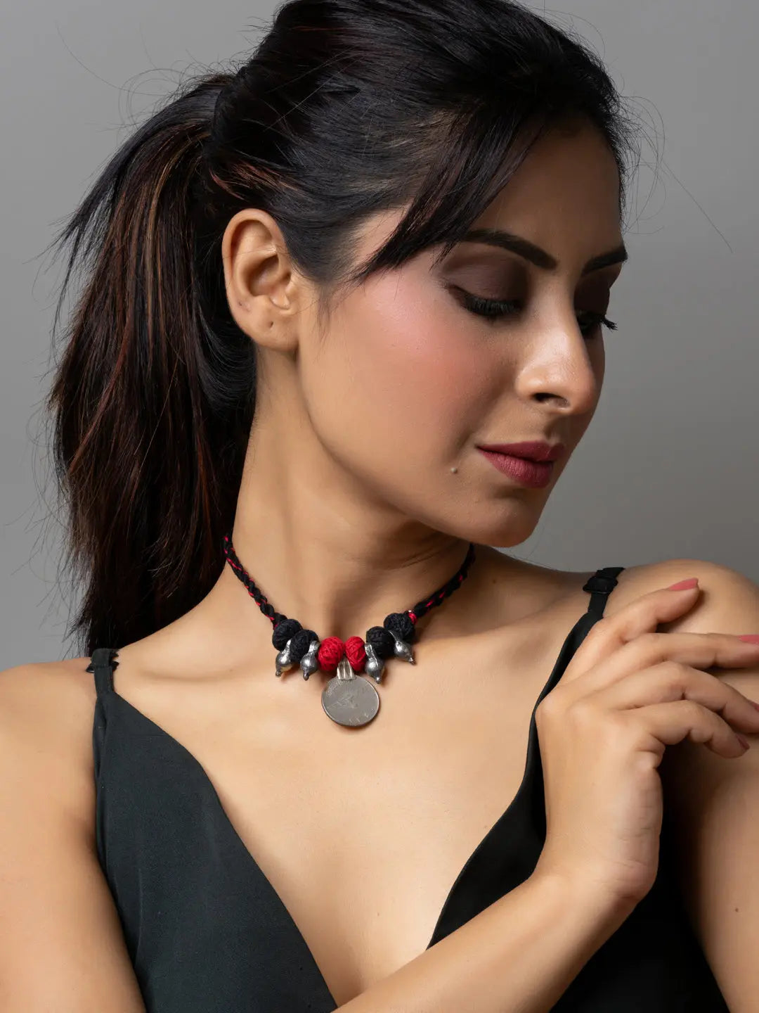 Woman wearing a black dress and stylish afghani pendant necklace with silver charm and red beads