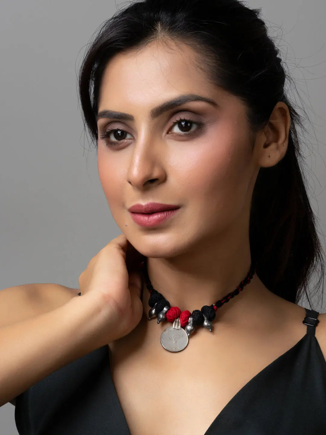 Elegant afghani pendant necklace with black and red beads worn by woman with black top