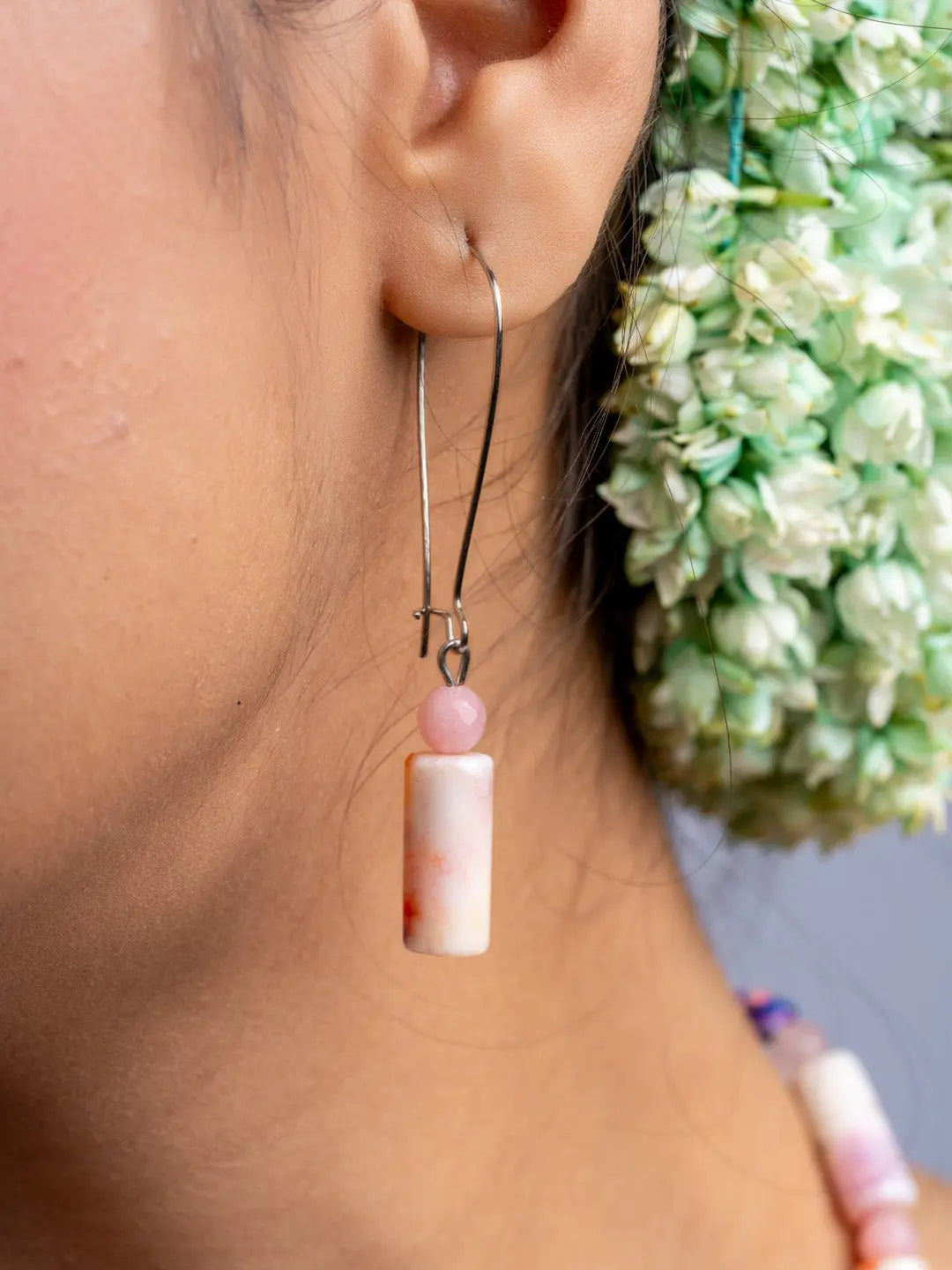 Woman wearing a handmade agate necklace and matching earring with pink and white beads