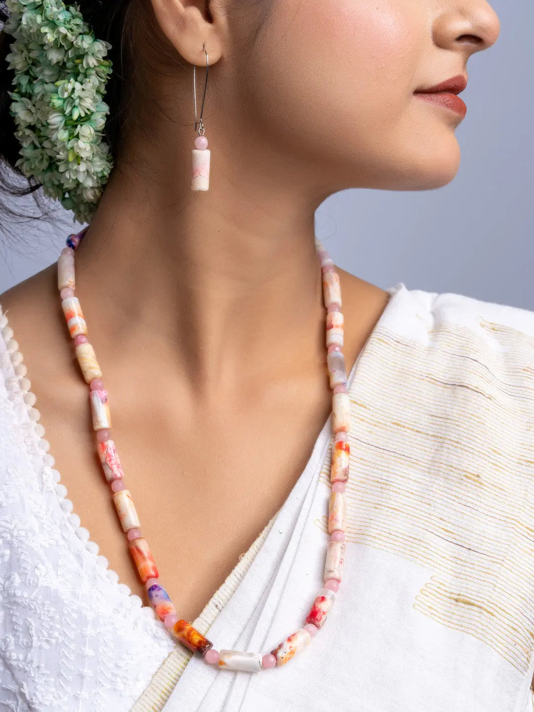 Handmade agate necklace with cylindrical multicolored beads worn with matching earrings