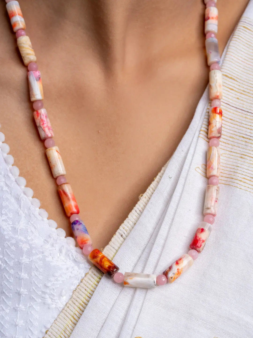 Handmade agate necklace with multicolored rectangular beads worn over white fabric