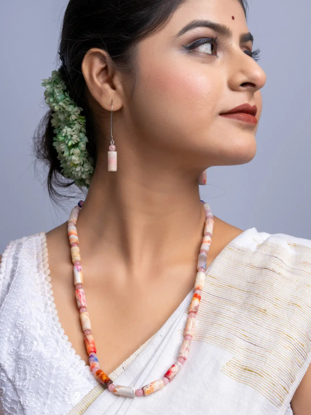 Handmade agate necklace with colorful beads worn by woman in traditional white attire