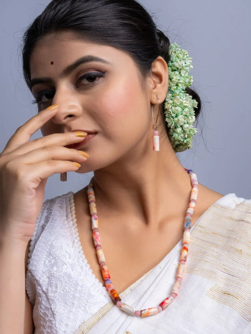 Handmade agate necklace with colorful beads worn by woman in white traditional attire and floral hair accessories