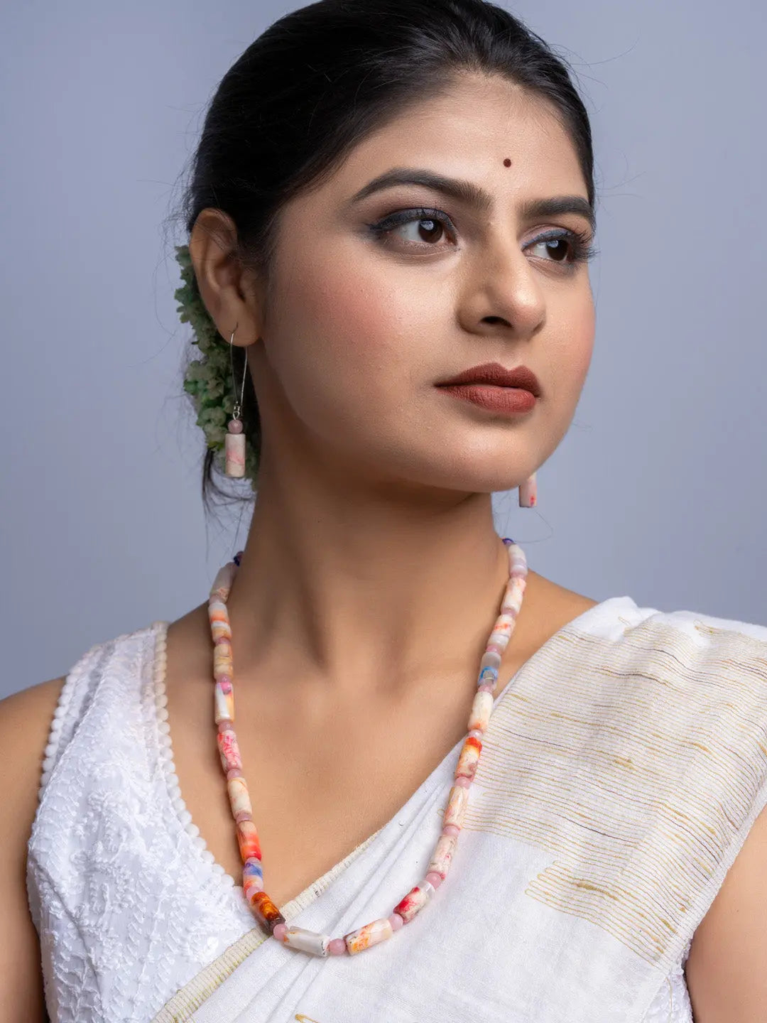 Woman wearing a handmade agate necklace with matching earrings and traditional white attire