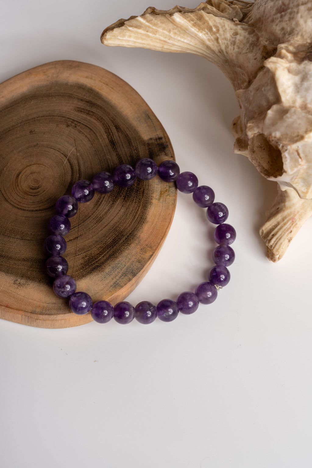 Amethyst stone bracelet on a wooden plate, showcasing its rich purple hues and natural beauty