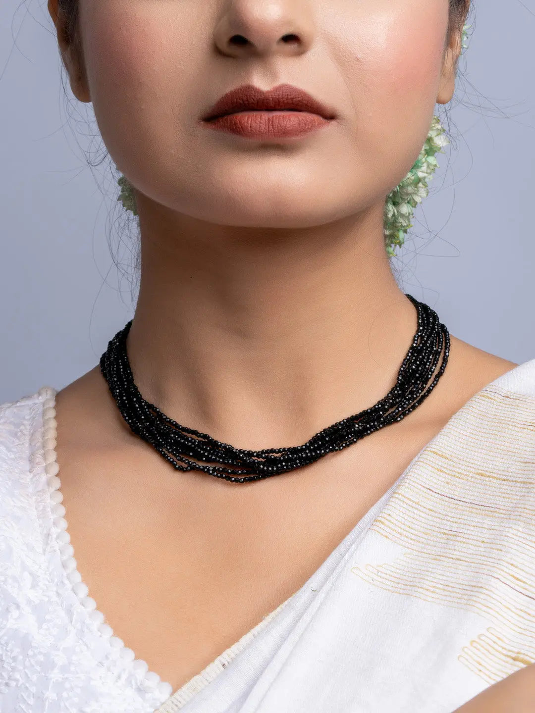 Handmade black crystal necklace with multiple strands worn by woman in white attire