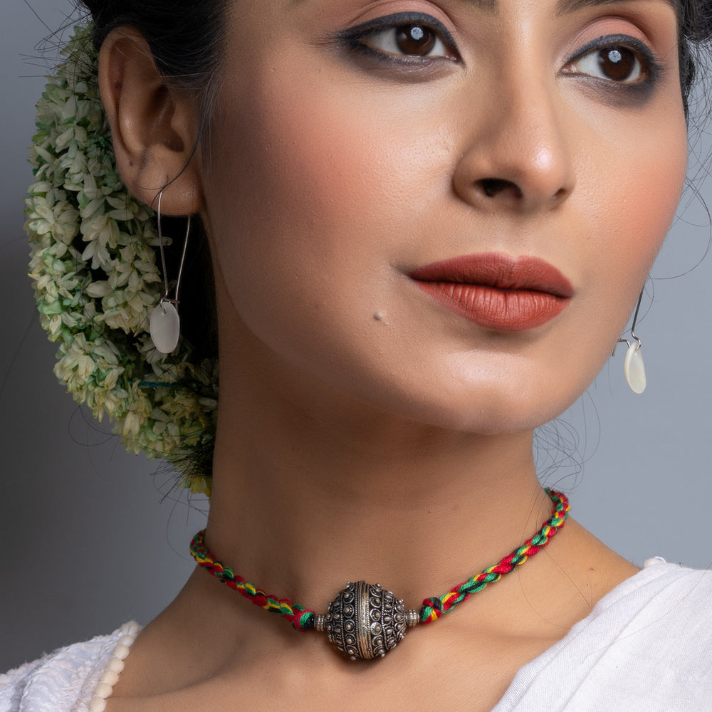 Handmade german silver choker necklace with intricate bead on colorful braided cord worn by woman