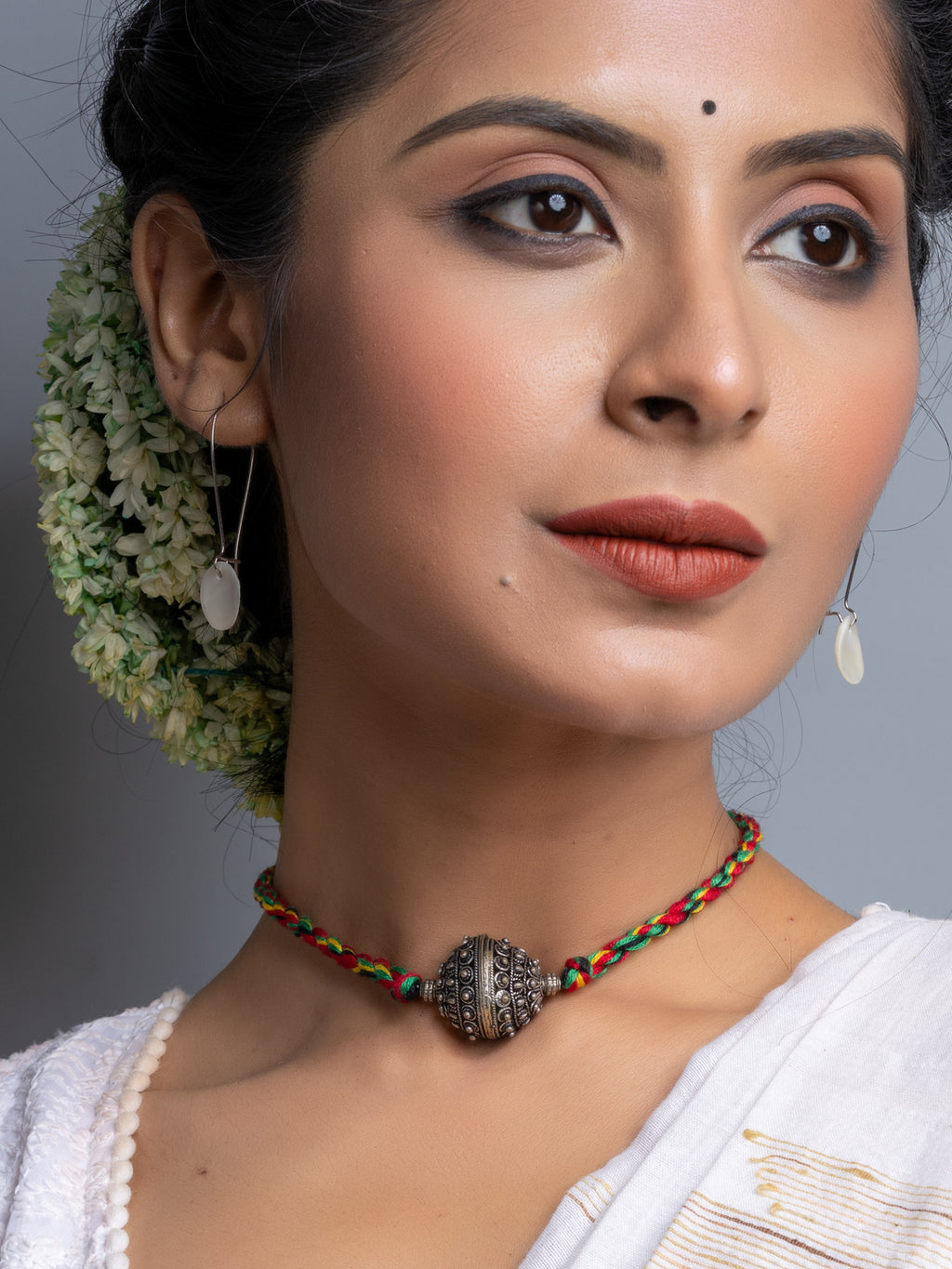 Handmade german silver choker necklace with intricate bead on colorful braided cord worn by woman