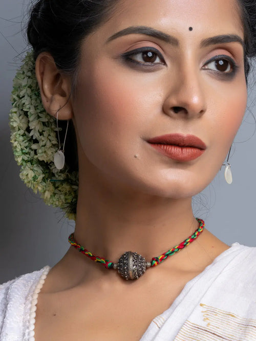 Handmade german silver choker necklace with intricate bead on colorful braided cord worn by woman