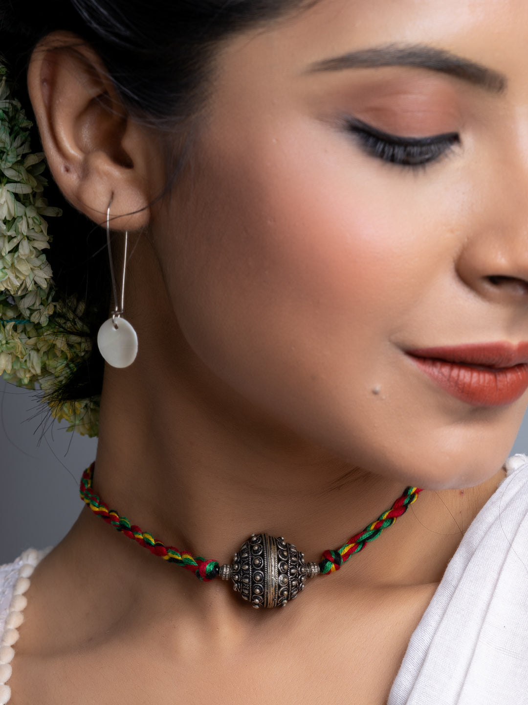 Close-up of a woman wearing a handmade german silver choker necklace with colorful braided cord and intricate pendant