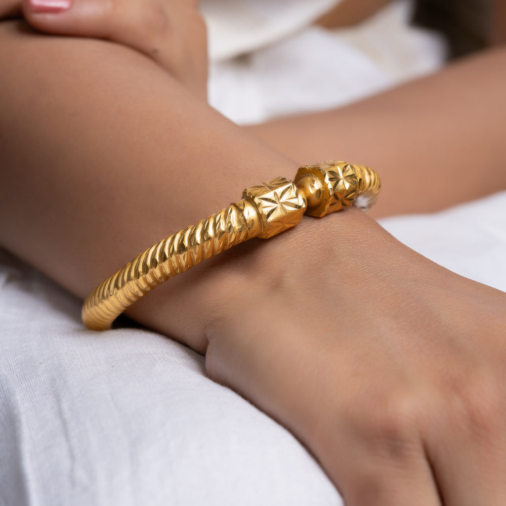 gold plate bangle from LOOK AND ADORN worn on a model wrist with twisted rope design and ornate end caps